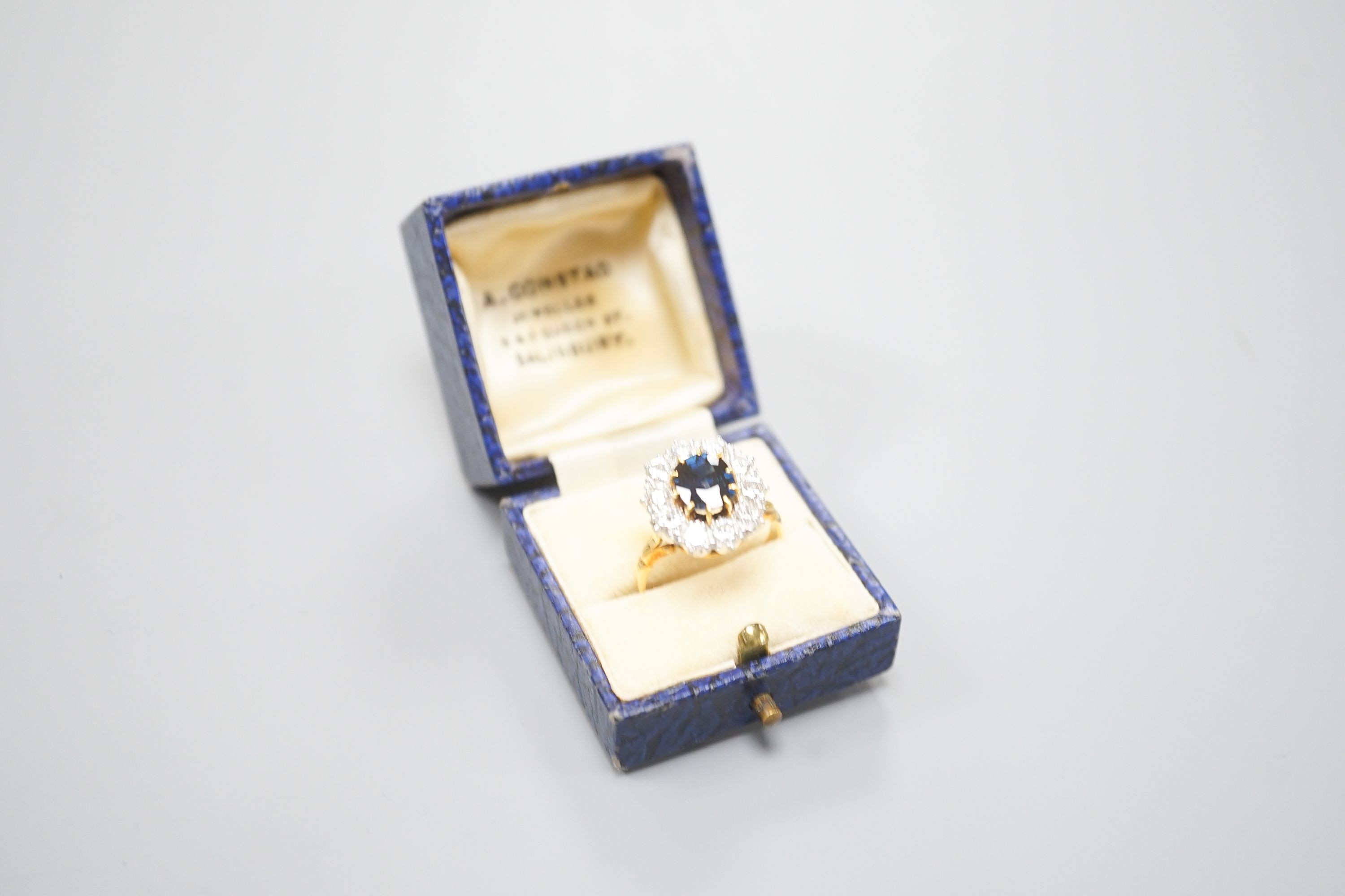 A modern 18ct gold, sapphire and diamond set oval cluster ring, size P/Q, gross weight 6.2 grams.